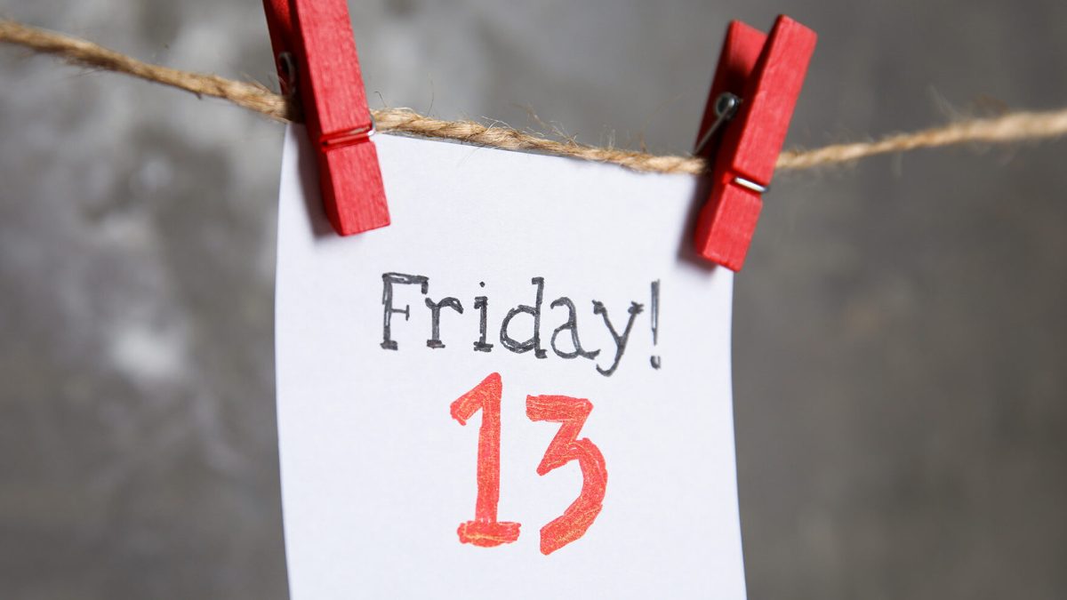 Paper note with phrase Friday! 13 hanging on twine against grey background. Bad luck superstition